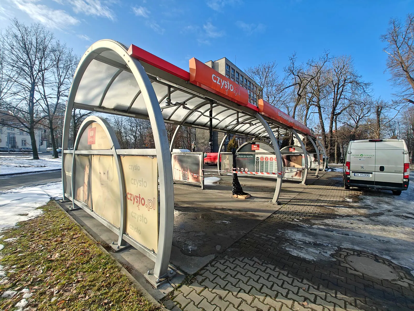 Stare oznakowanie i banery na łukowej konstrukcji myjni w Zabrzu